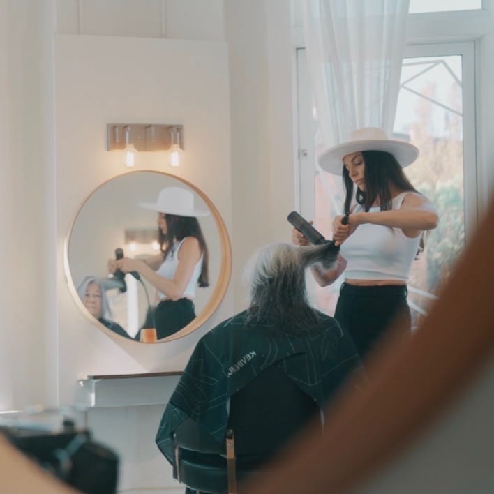 Styling client's long hair in bright salon